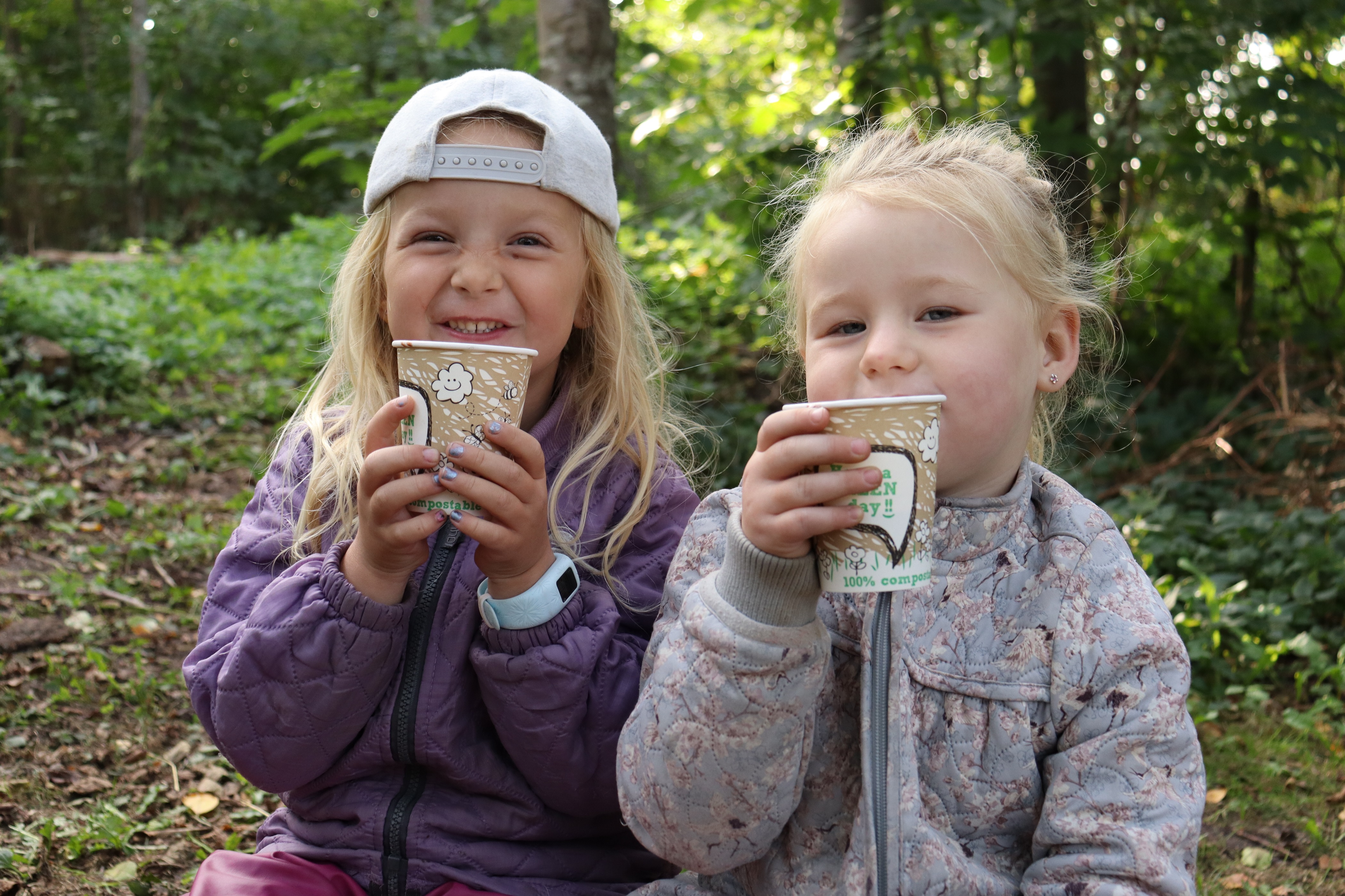 Piger sidder og drikker varm kakao af kop udenfor