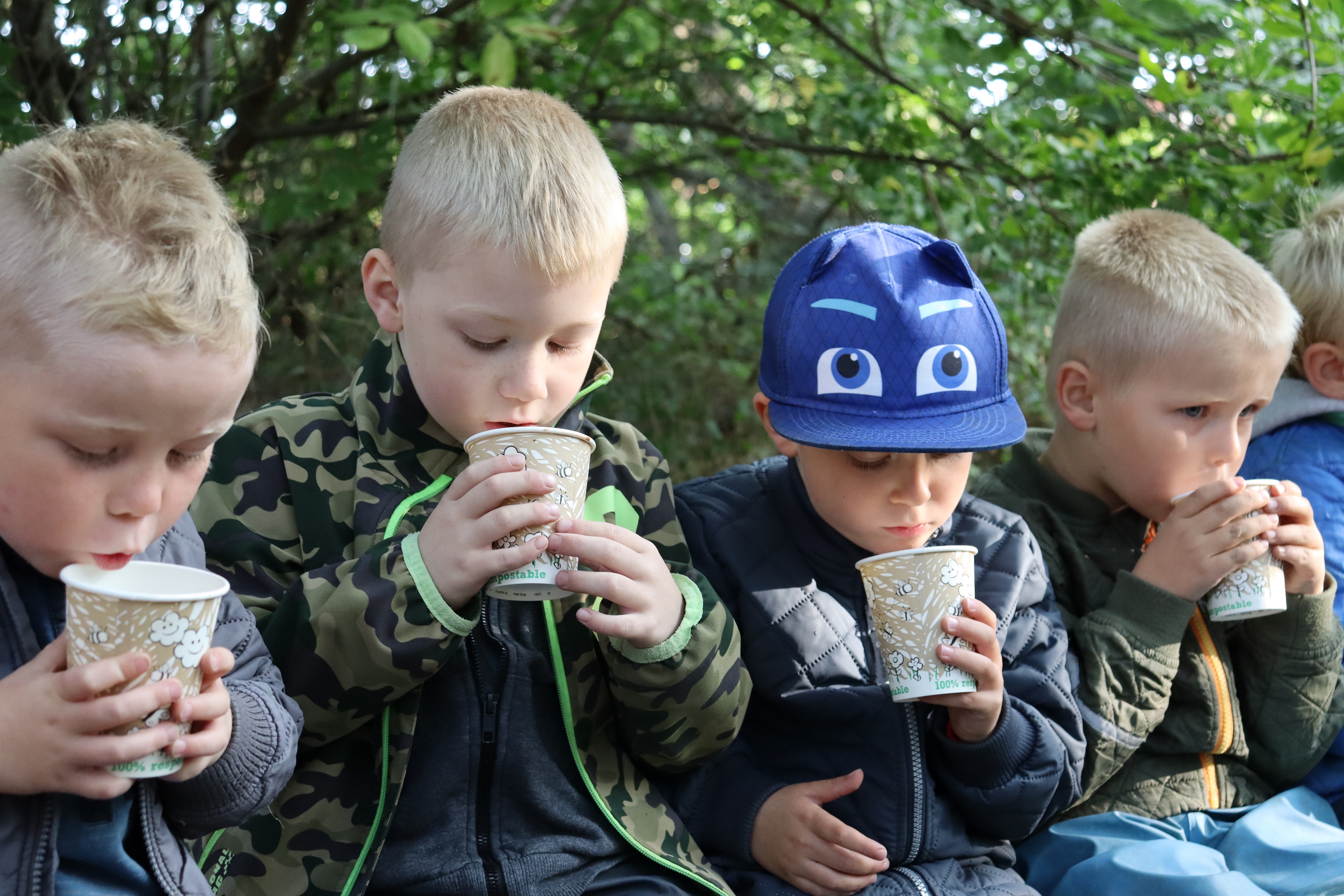 Drenge sidder og drikker varm kakao af kop udenfor