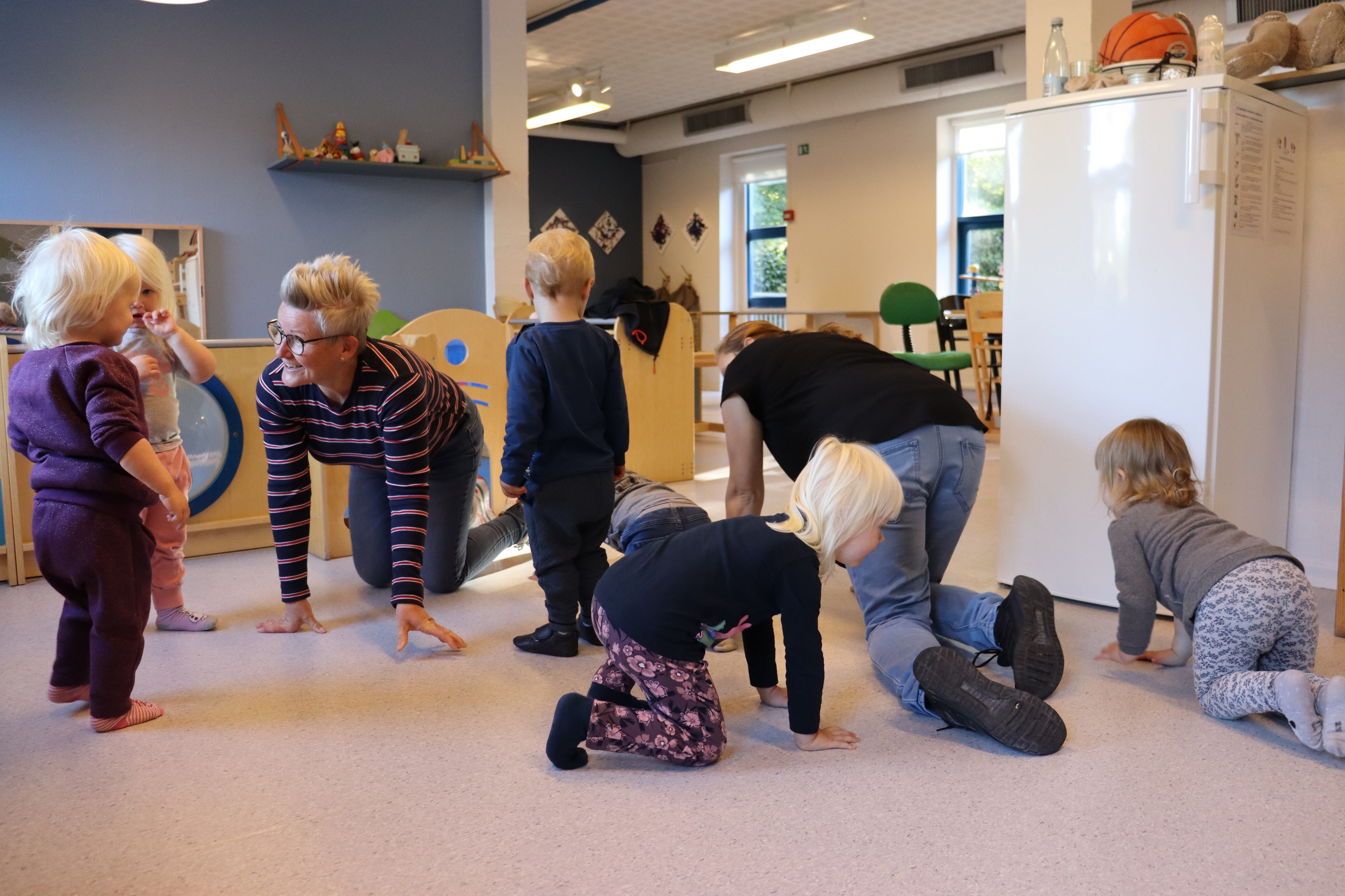 Vuggestuen leger lege, hvor de to pædagoger kravler rundt på gulvet sammen med børnene